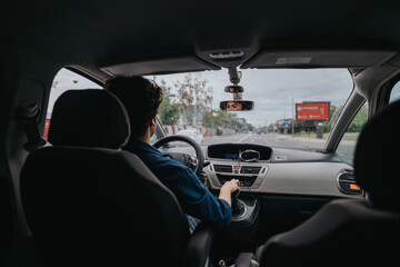 A man is seen from behind driving a car through a city street. The focus is on the driver...