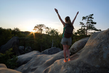 Young woman hiker standing alone with outstretched arms on mountain footpath enjoying view of evening nature on wilderness trail. Active way of life concept