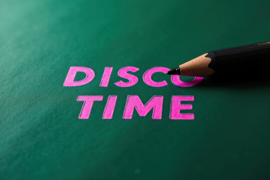 Pen laying on dark green paper with the words 'Disco Time' in pink color. Time for break of work