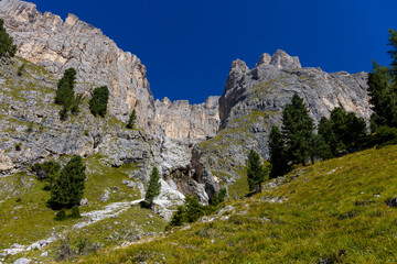 Sunny day in the Dolomites. Rocky mountain peaks of Dolomiti Alps in summer under the blue sky with some clouds prominent mountain summits landscape and stunning views of the alpine range and meadow