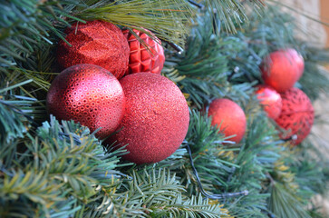 Red balls christmas decorations on a pine tree garland. Closeup photo outdoors. Christmas tree decorations.