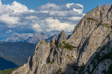 Obraz premium Sunny day in the Dolomites. Rocky mountain peaks of Dolomiti Alps in summer under the blue sky with some clouds prominent mountain summits landscape and stunning views of the alpine range and meadow