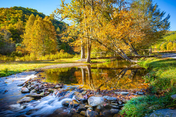 Beautiful fall scene with water, a bridge and a small waterfall
