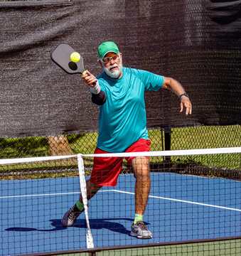 Pickleball player leans in to strike a sharp volley.