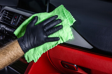 Hand cleaning the car interior with green microfiber cloth. Hand with microfiber cloth cleaning leather seat,auto detailing and valeting concept,washing car care interior.