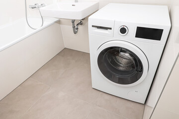 Modern washing machine in light bathroom