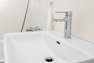 White sink with silver tap in light bathroom, closeup