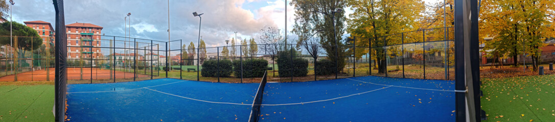 outdoor padel court with a blue surface, equipped with net floodlights and glass © manola72