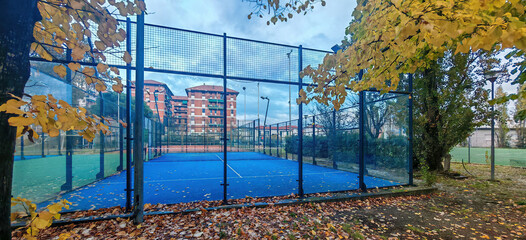 outdoor padel court with a blue surface, equipped with net floodlights and glass © manola72