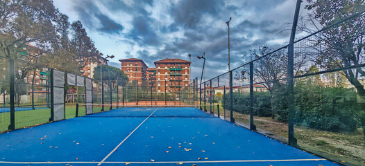 outdoor padel court with a blue surface, equipped with net floodlights and glass © manola72