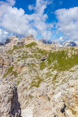 Sunny day in the Dolomites. Rocky mountain peaks of Dolomiti Alps in summer under the blue sky with some clouds prominent mountain summits landscape and stunning views of the alpine range and meadow