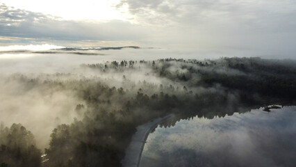 Beautiful tranquil lakeside campsite in the morning surrounded by lush green trees and fog