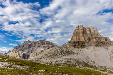 Sunny day in the Dolomites. Rocky mountain peaks of Dolomiti Alps in summer under the blue sky with some clouds prominent mountain summits landscape and stunning views of the alpine range and meadow
