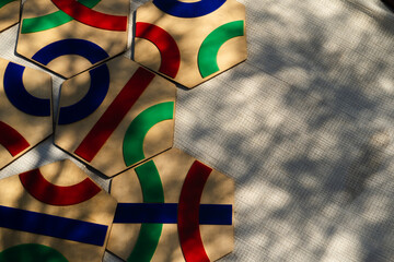 flat lay image of hexagonal wooden tiles with vibrant geometric patterns in red, blue, and green.