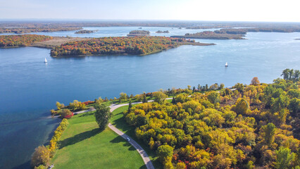 Breathtaking scenic view of a serene lake surrounded by vibrant autumn trees and a clear blue sky.
