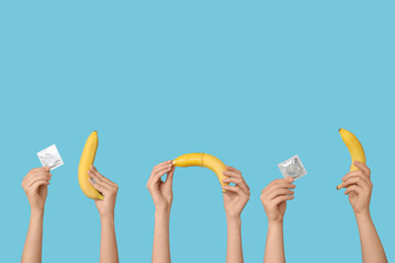 Female hands with condoms and bananas on color background