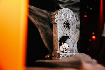 A spooky scene with cobweb covered tombstone, a skull and dim lighting
