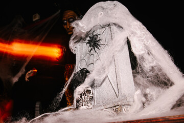 A spooky scene with cobweb covered tombstone, a skull and dim lighting