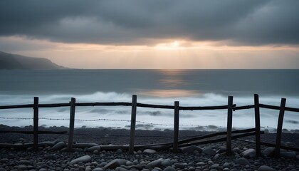 Obraz premium a wooden fence and rocks by the ocean