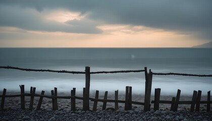 Obraz premium a wooden fence and rocks by the ocean