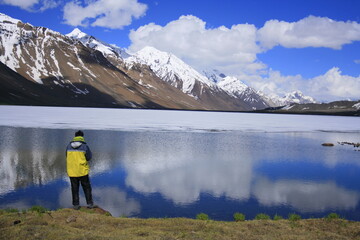 A lone adventurer enjoying the majestic view of a half frozen lake in summer