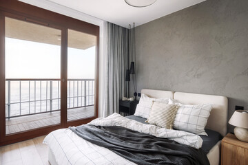 Modern bedroom interior with balcony view overlooking the ocean at sunrise