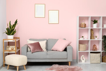 Comfortable sofa, shelving units and pouf in living room
