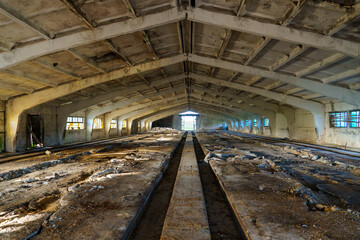 An abandoned destroyed barn, cowshed, warehouse or hangar from the inside. An old abandoned concrete bunker. Ammunition depot from inside in low light