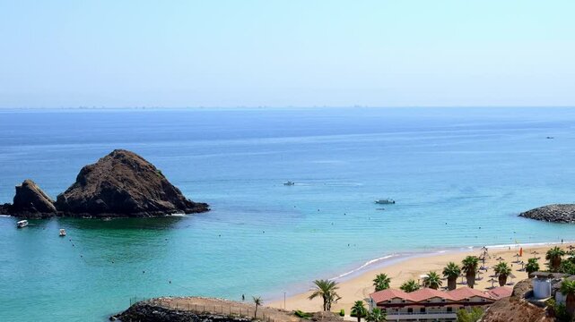 Snoopy Island in Fujairah, UAE. Aerial view of the beach with turquoise waters, a rocky island and a resort nearby