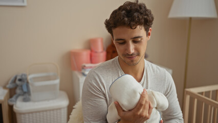 Young man holding baby in cozy bedroom, displaying tenderness and warmth, with a cradle nearby...