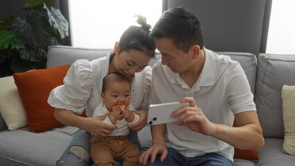 Family capturing a selfie together includes mother, father, and baby in a cozy living room setting, showcasing love and togetherness in a warm, comfortable home interior.