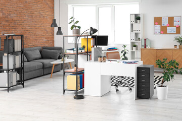 Interior of modern office with workplace, shelf units and sofa