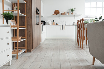 Interior of light kitchen with white counters and shelf unit