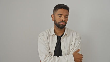 A young african american man with a beard stands with arms crossed against a white background, radiating confidence and style.