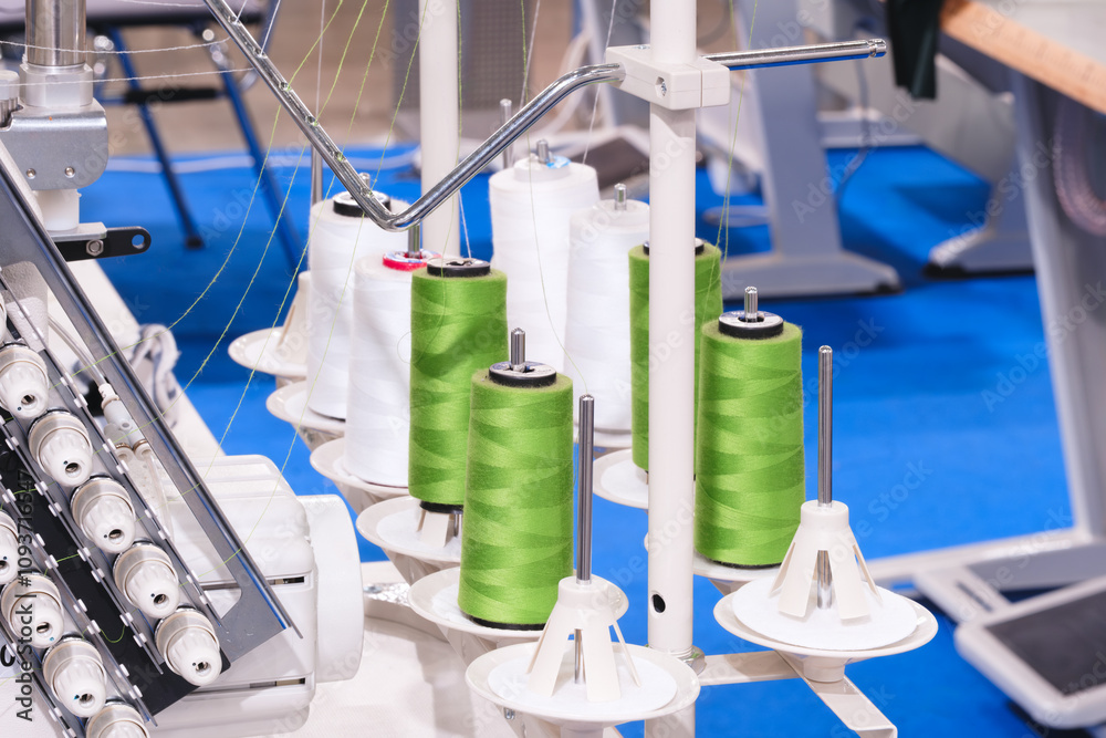 Leinwandbilder A machine with green and white threads on it. There are six green threads on the machine. The machine is in a room with blue walls