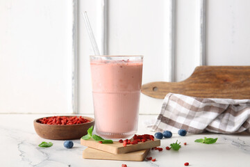 Glass of fresh goji berry smoothie with blueberries and mint on white background