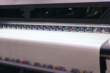 A machine is printing a white sheet of paper with a colorful design. The machine has a lot of...