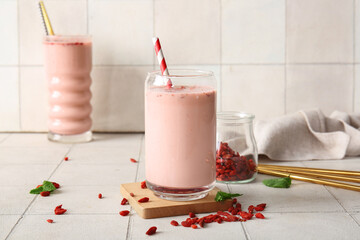 Glasses of fresh goji berry smoothie with mint on white tile background