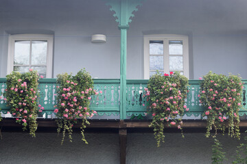 Carved balconies of the house are decorated with pots with blooming ampel geraniums
