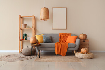 Interior of cozy living room with sofa, shelf unit and autumn decor