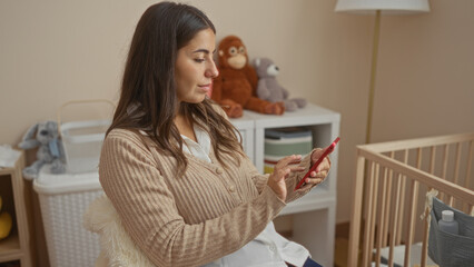 Woman checking phone in cozy bedroom beside cradle surrounded by plush toys, creating a nurturing environment with a modern touch, highlighting femininity and relaxation.