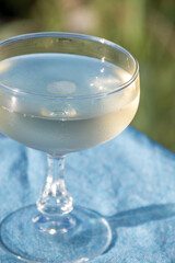 Cold sparkling wine, cava or champagne in two coupe glasses on table with blue sea water view