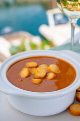 Homemade tasty fish or bisque soup with croutons served with glass of cold white wine and view on...