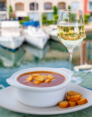 Homemade tasty fish or bisque soup with croutons served with glass of cold white wine and view on...