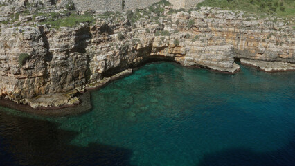 Fototapeta premium Scenic view of rocky cliffs and clear turquoise sea water in polignano a mare, puglia, italy, capturing the beauty of the mediterranean coastline in a serene outdoor setting.