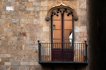 Balcony with cast iron railings and rectangular balcony door with shaped arch on old stone block wall. From the Peace door series.