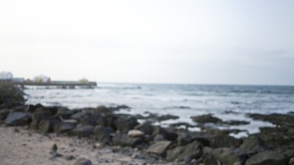 Blurred seashore in lanzarote, spain, with an out-of-focus pier and rocks, capturing the serene coastal atmosphere of the canary islands.
