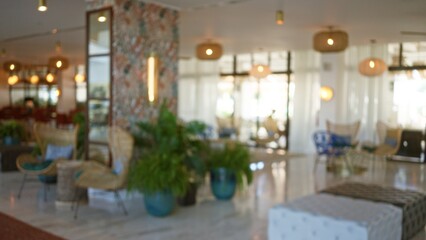 Blurred view of modern hotel lobby with bokeh lights, stylish furniture, and lush indoor plants creating a welcoming, tranquil atmosphere