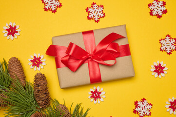 Gift box with red satin ribbon and bow on a yellow background. Holiday background