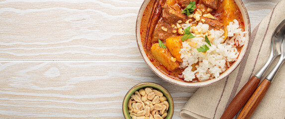 Aromatic massaman curry, a staple of thai cuisine, with tender beef, potatoes, and fluffy rice, garnished with peanuts and fresh herbs, a vibrant and flavorful dish of Thailand, copy space